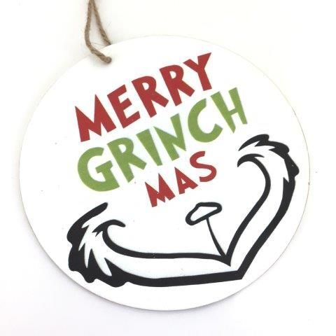 White disc hanging ornament with "MERRY GRINCHMAS" lettering and a grinch smile